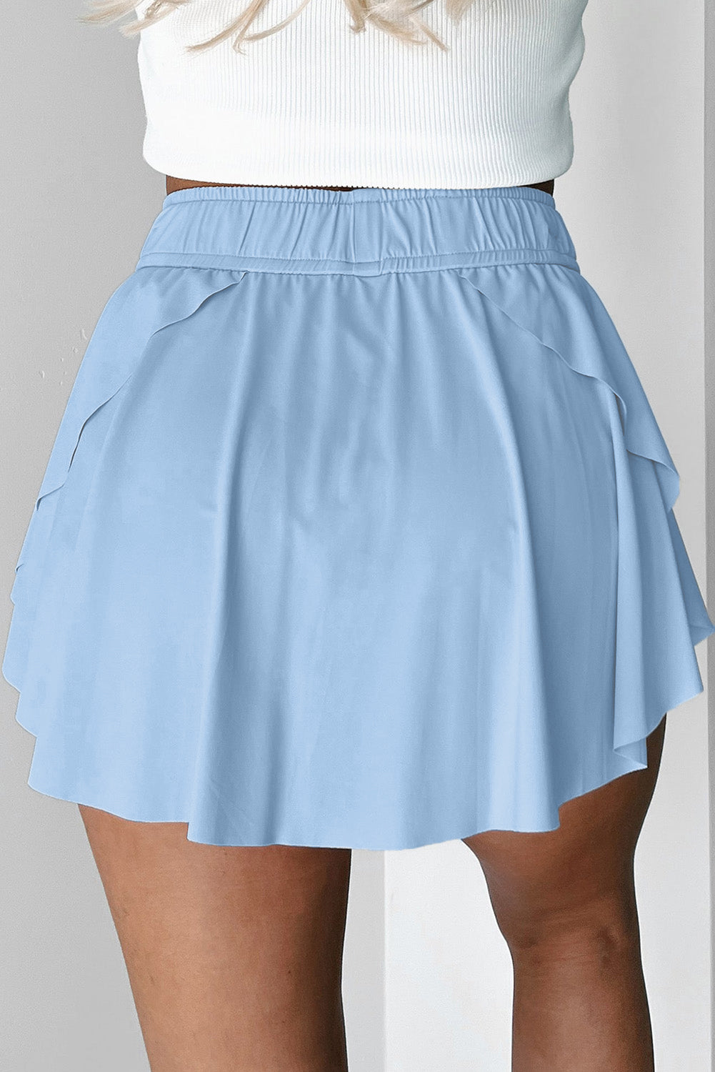 Light blue tennis skort worn by a person on a plain background back view