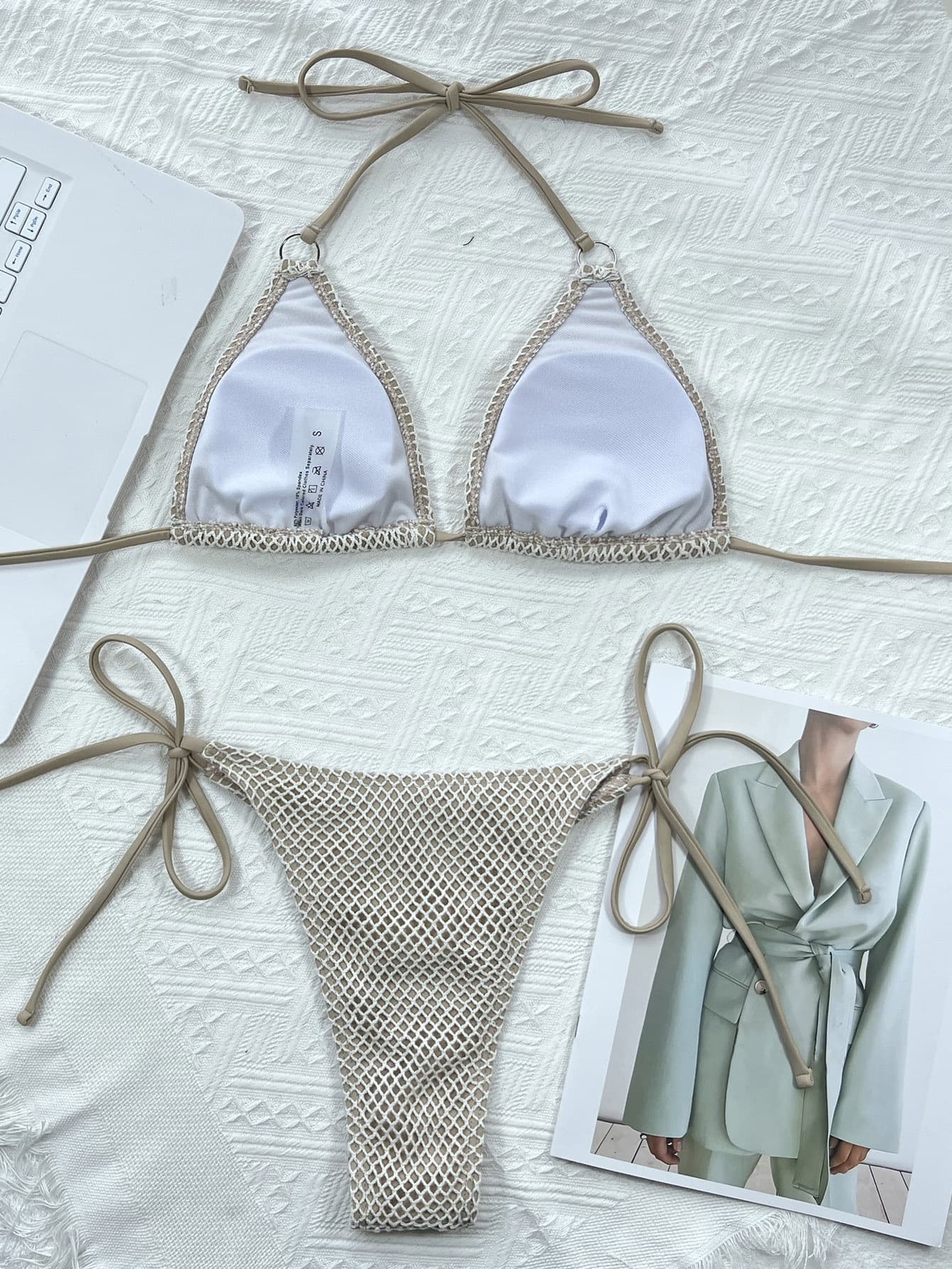 Bikini set with beige mesh bottom and white top on a textured surface.