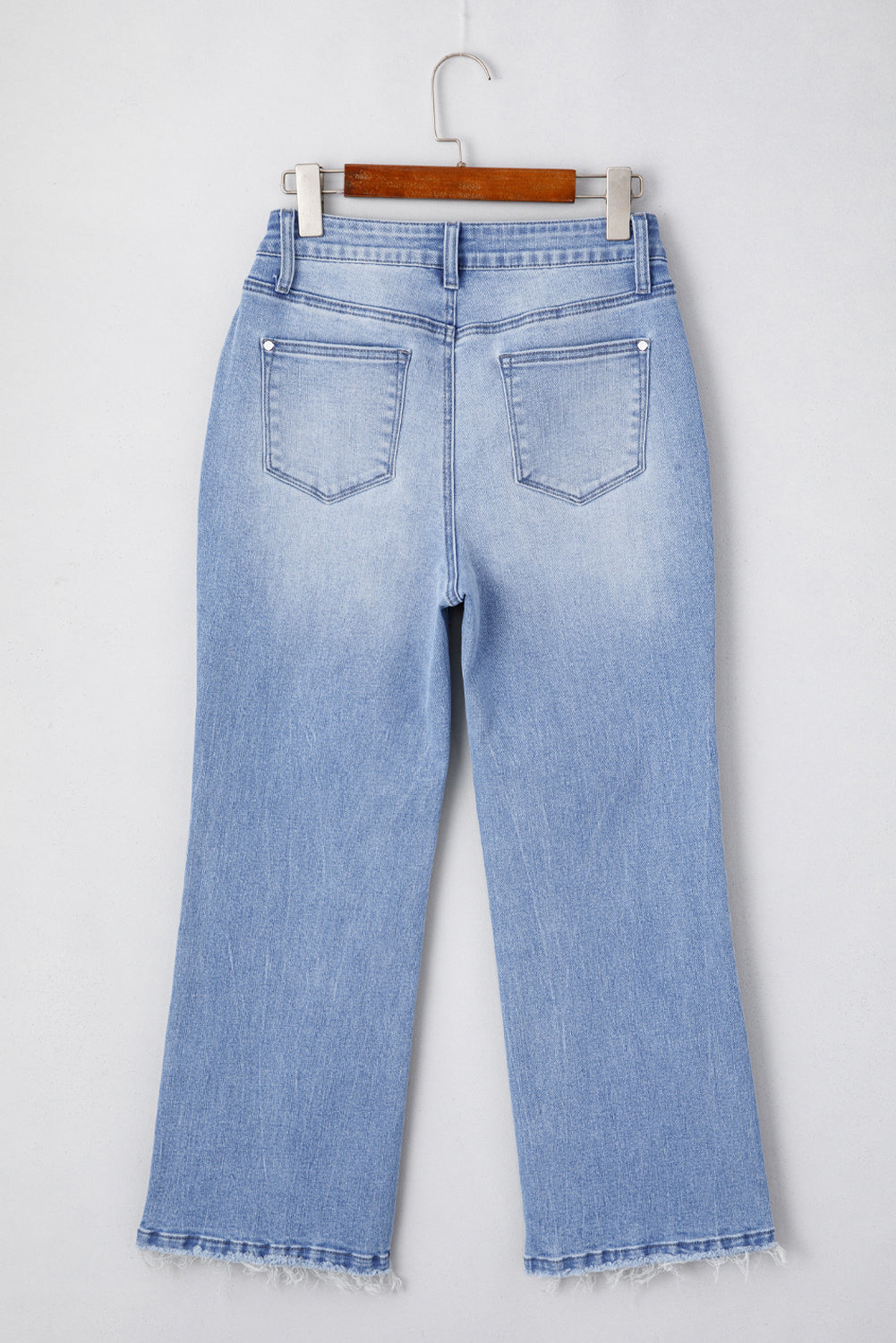 Light blue jeans on a hanger against a white background