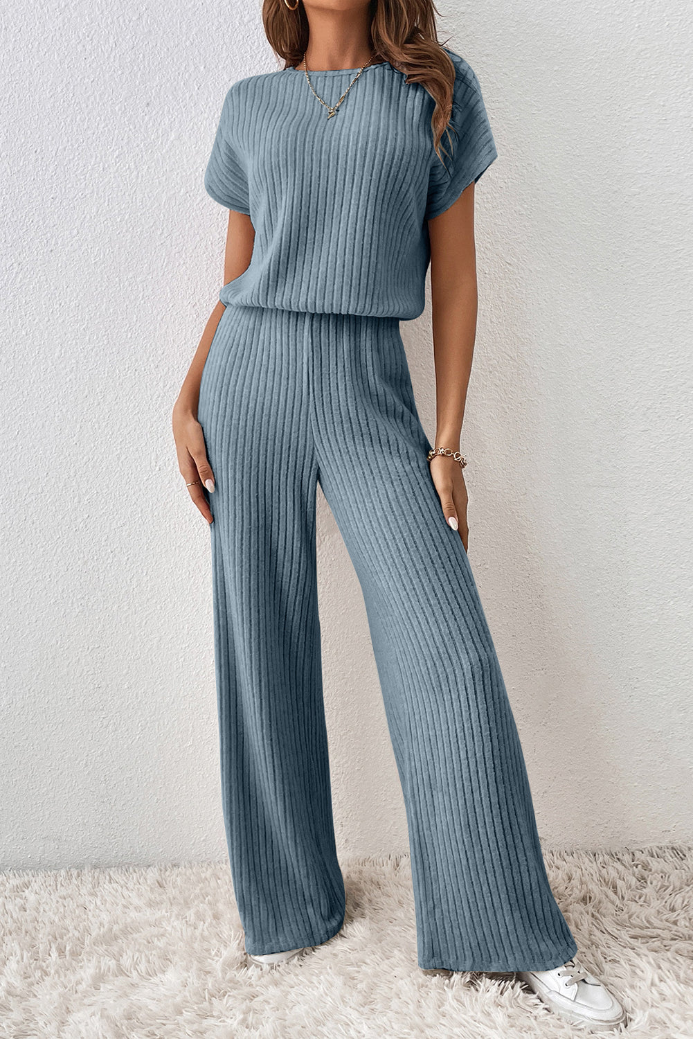 Woman wearing a matching ribbed top and pants set against a light background