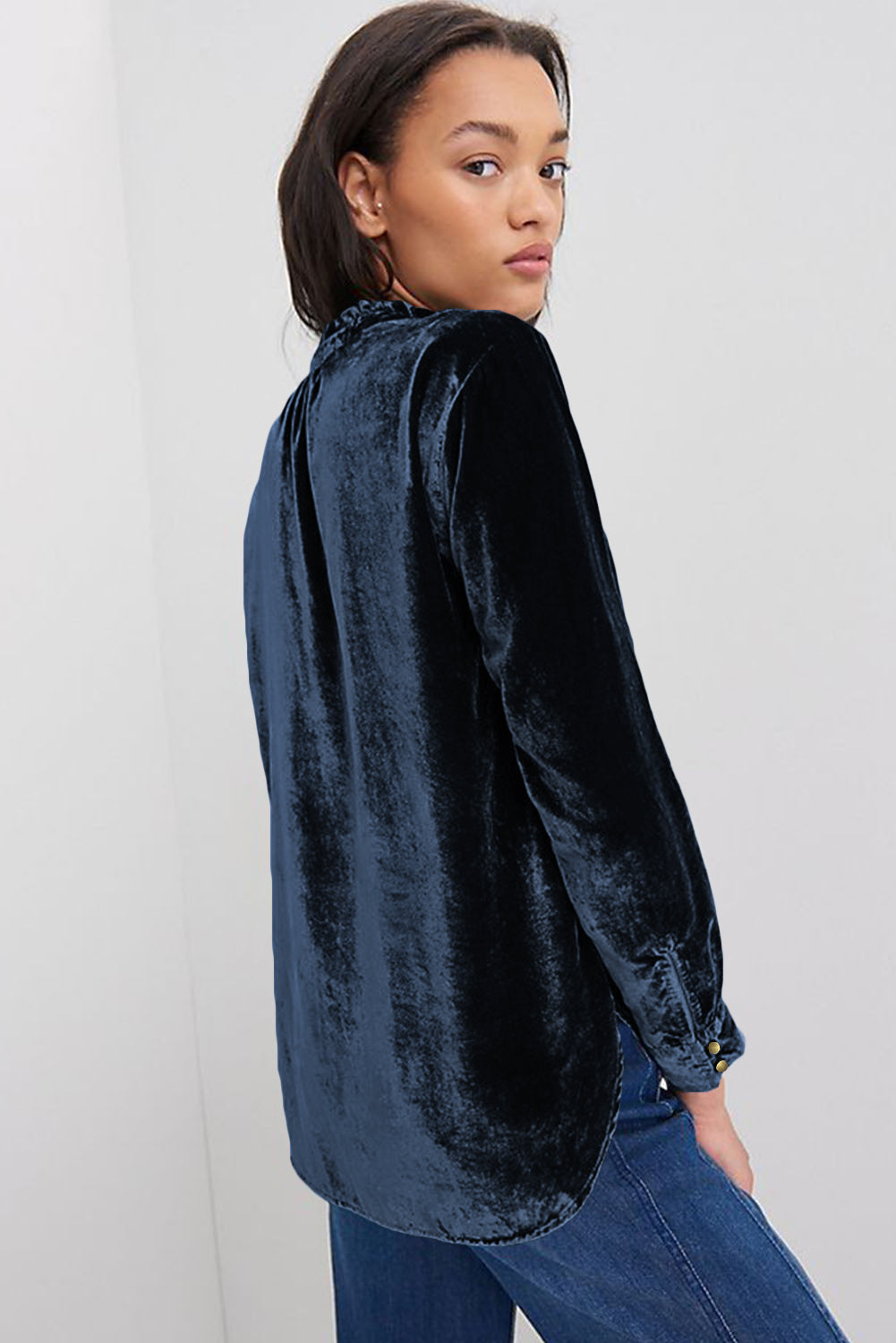 Woman wearing a dark blue velvet shirt against a white background