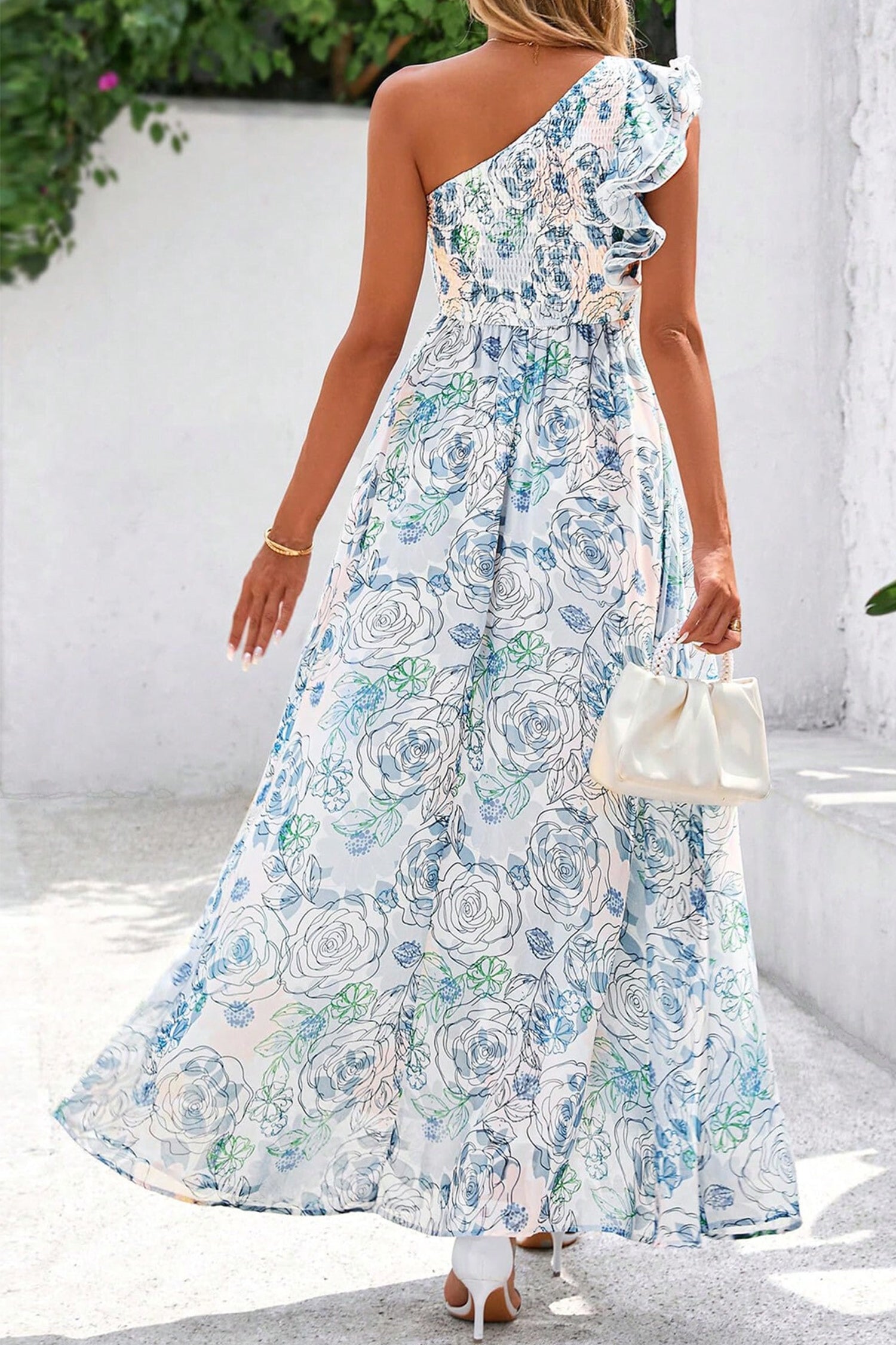 Woman wearing a floral one-shoulder dress with a white background back view