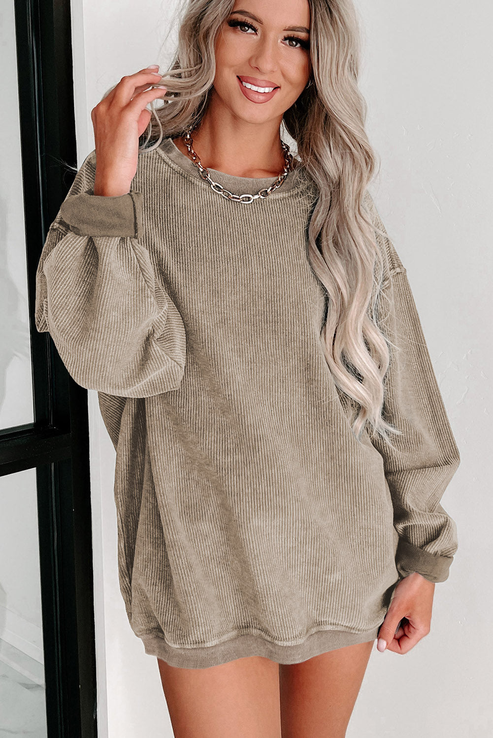 Woman wearing a beige corduroy dress with a white background