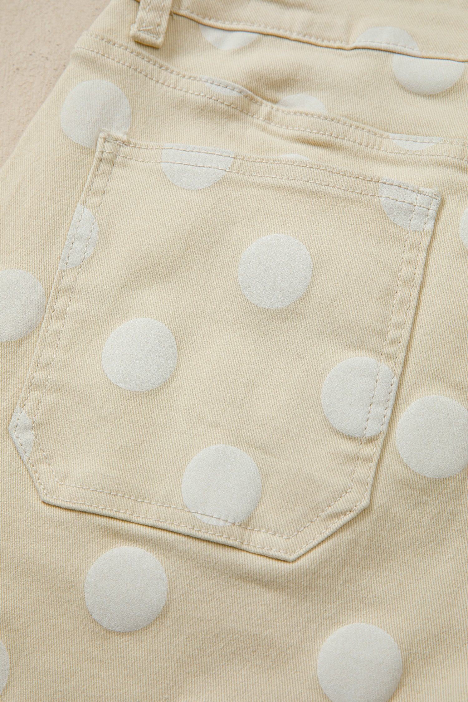 Close-up of beige pants back pocket view with white polka dots on a pocket