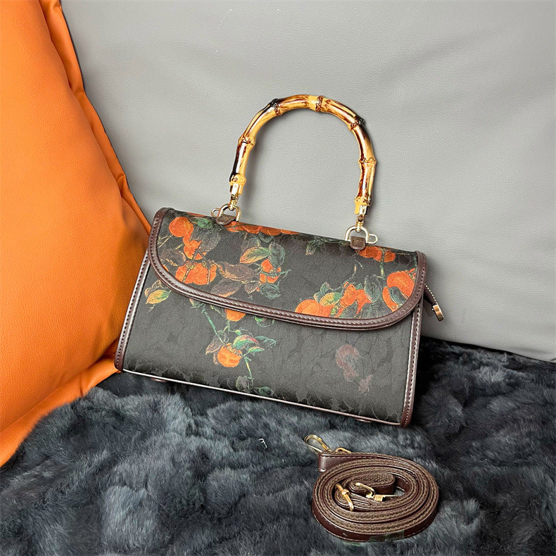 Floral-patterned handbag with bamboo handle on a textured surface