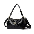Black patent leather handbag with gold accents on a white background