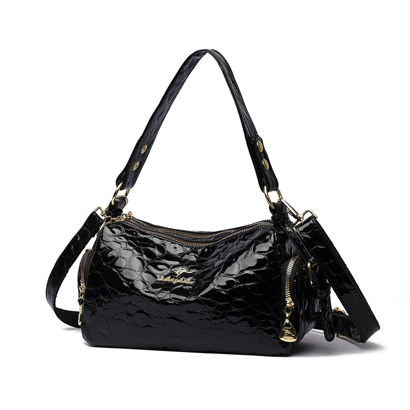 Black patent leather handbag with gold accents on a white background
