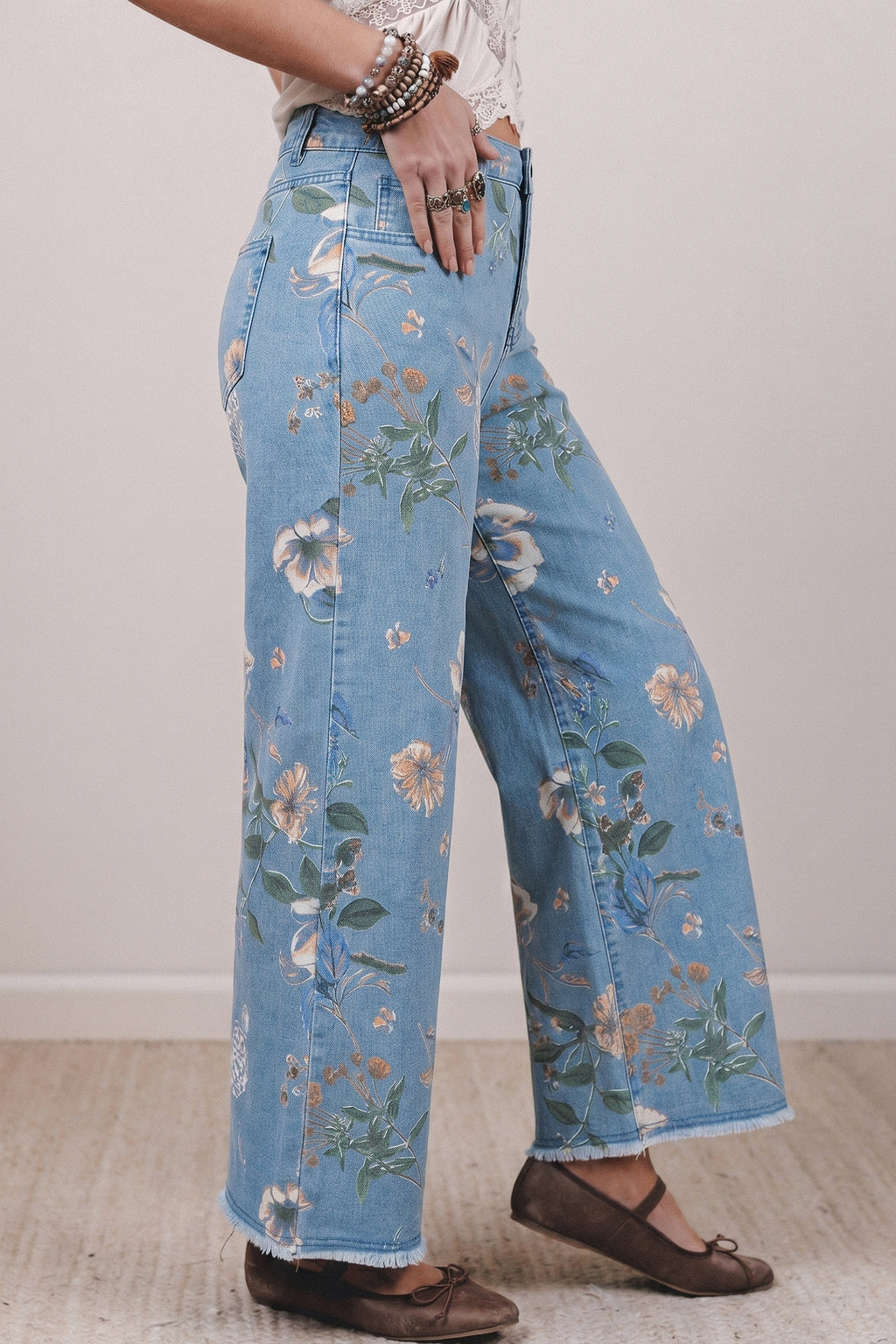Light blue jeans with floral patterns worn by a person on a plain background side view