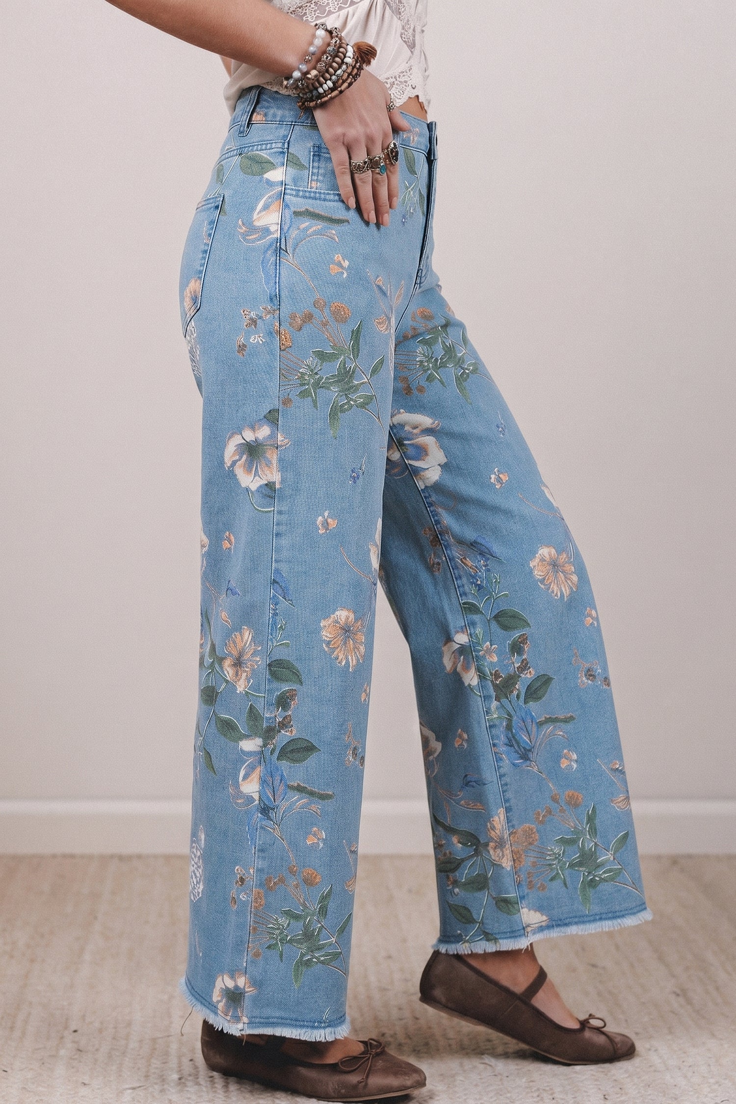Light blue jeans with floral patterns worn by a person on a plain background side view
