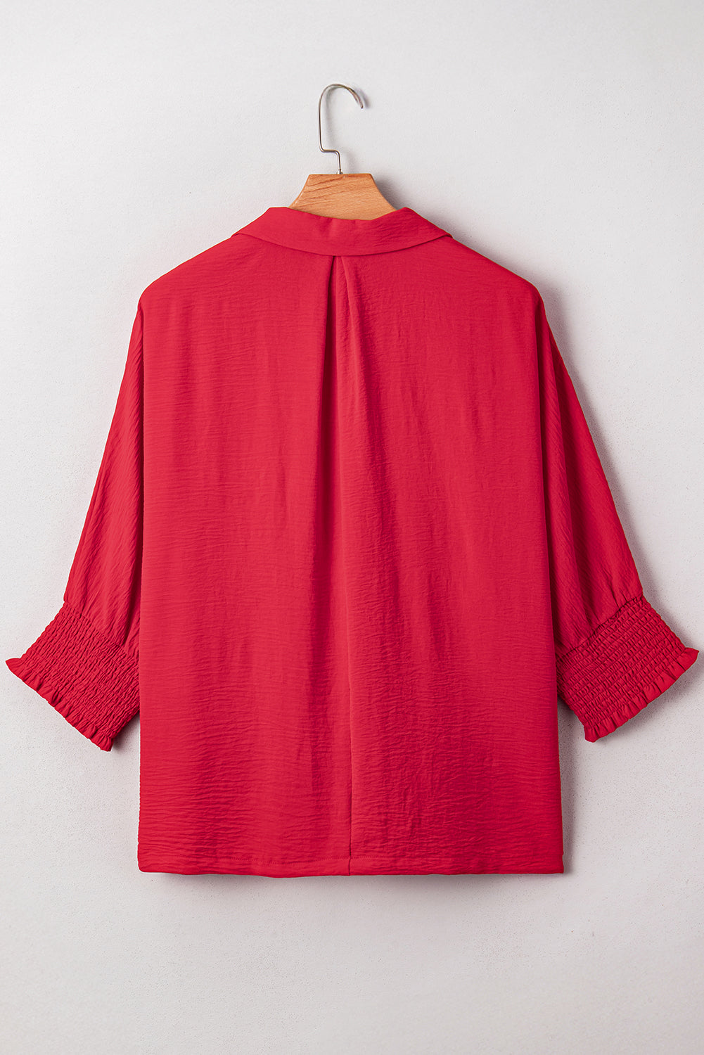 Red blouse on a hanger against a white background
