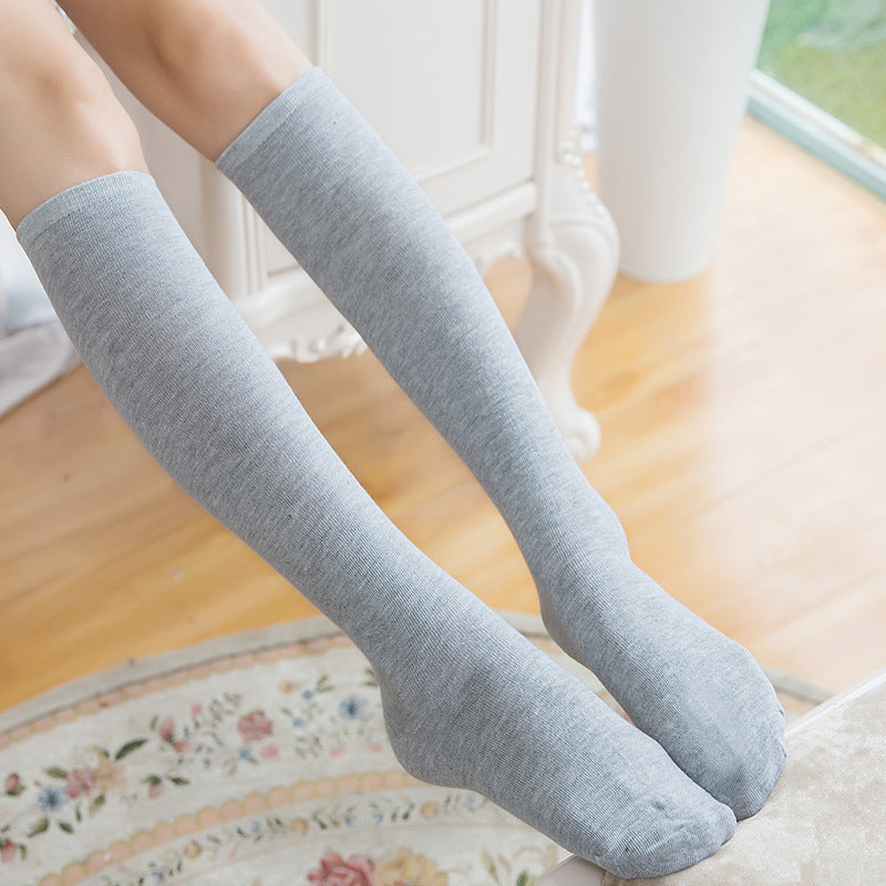 Gray knee-high socks worn by a person on a wooden floor.
