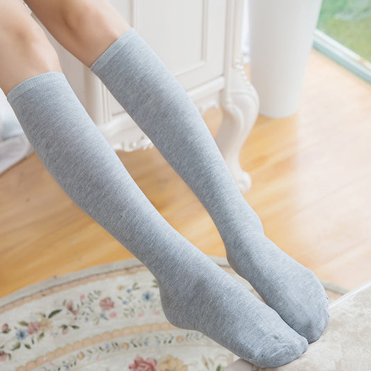 Gray knee-high socks worn by a person on a wooden floor.