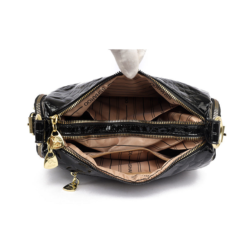 Black leather handbag with gold zipper and hardware on a white background