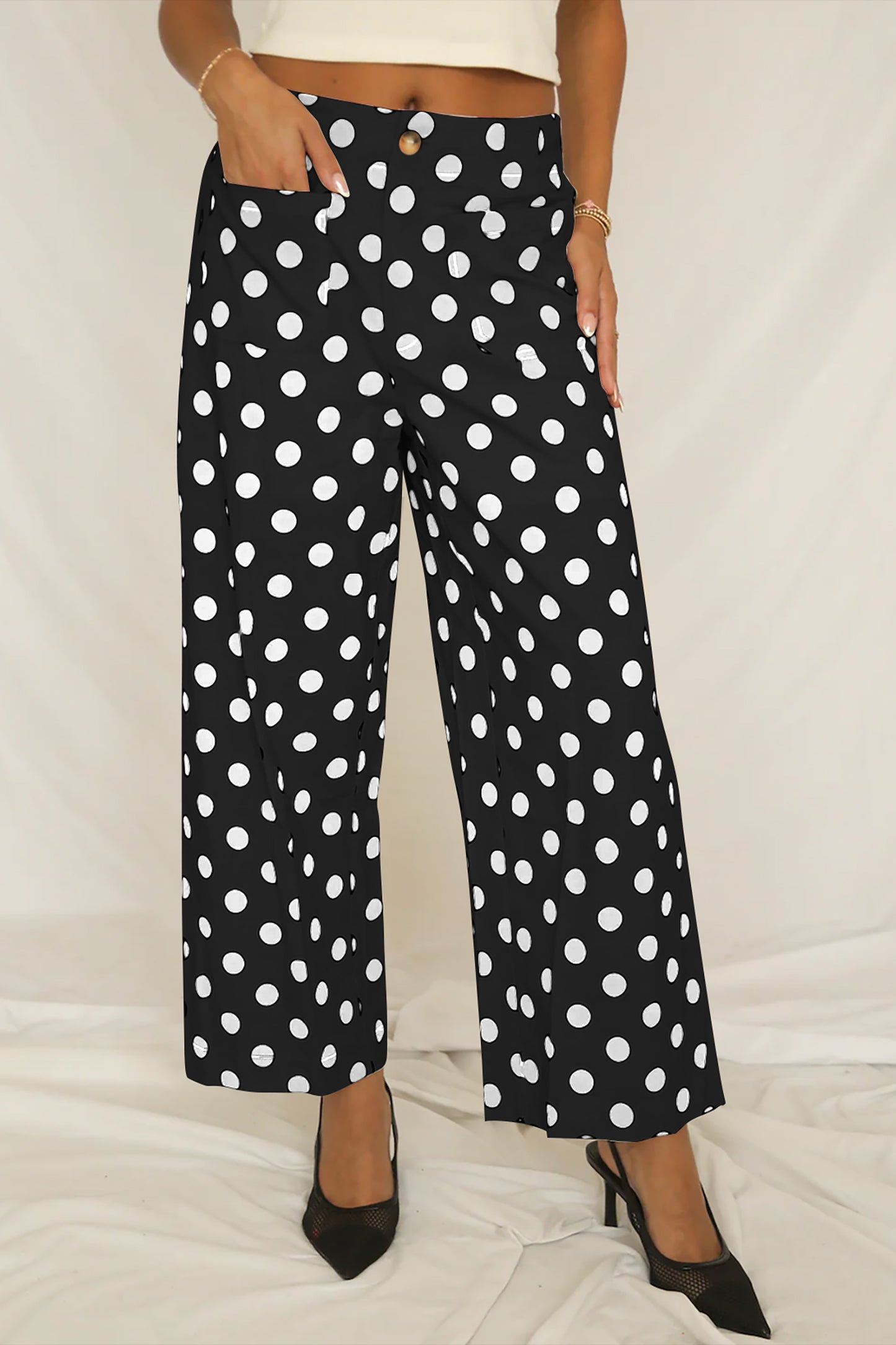 Person wearing black pants with white polka dots on a light background