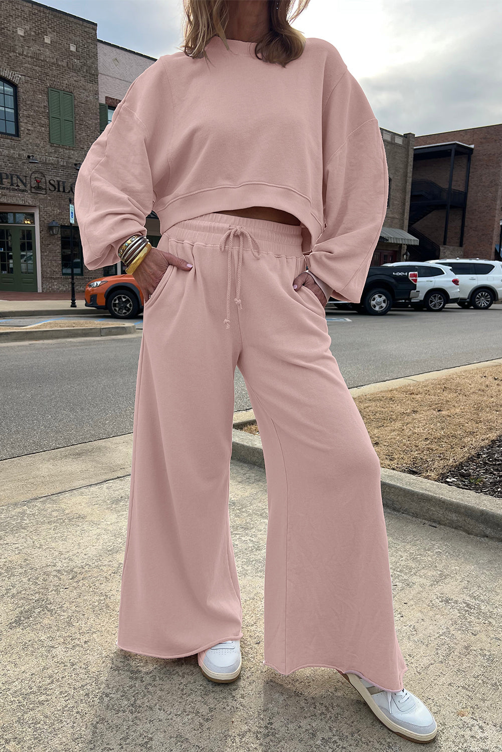 Person wearing a pink outfit standing on a street corner.