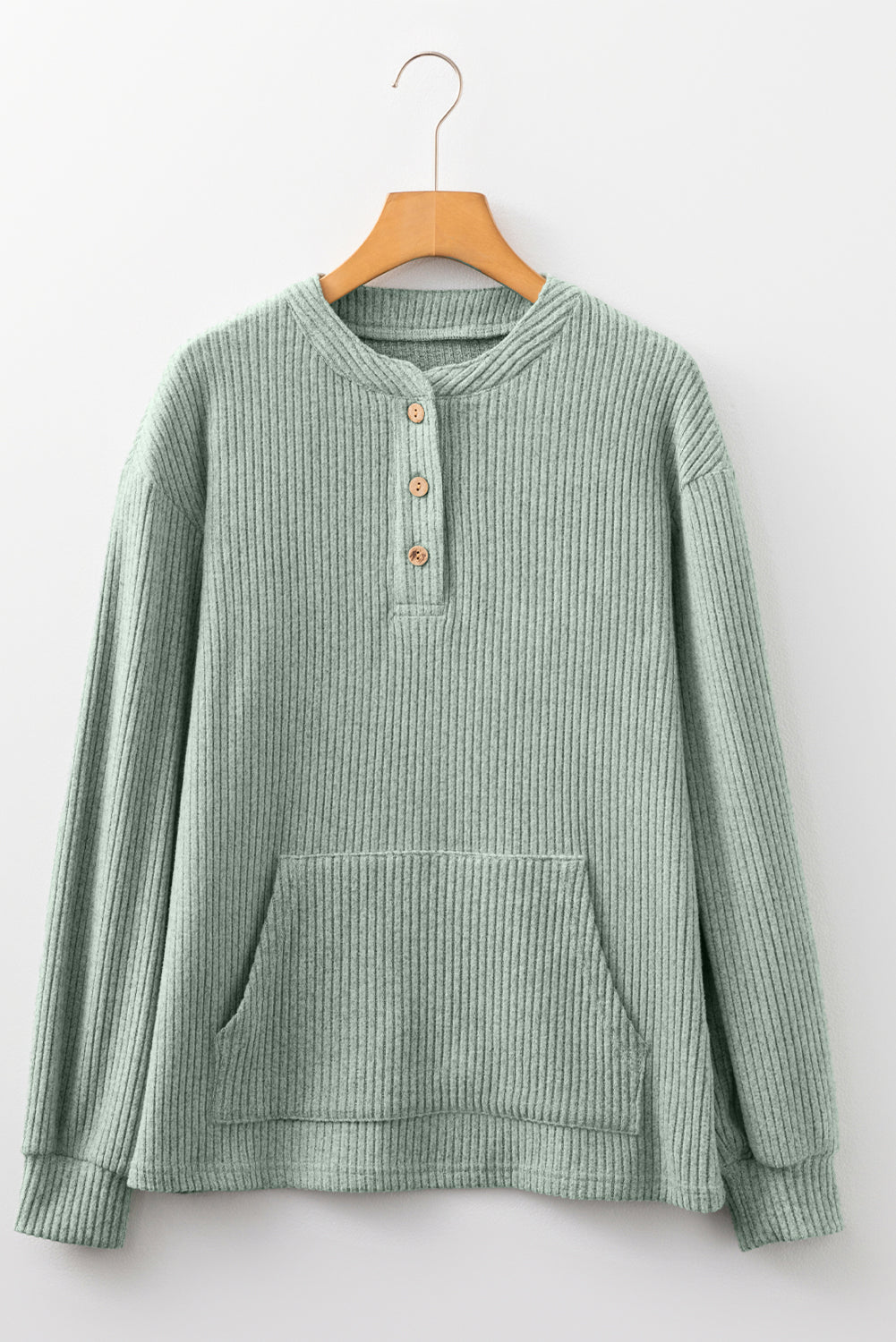 Green ribbed sweater on a hanger against a white background