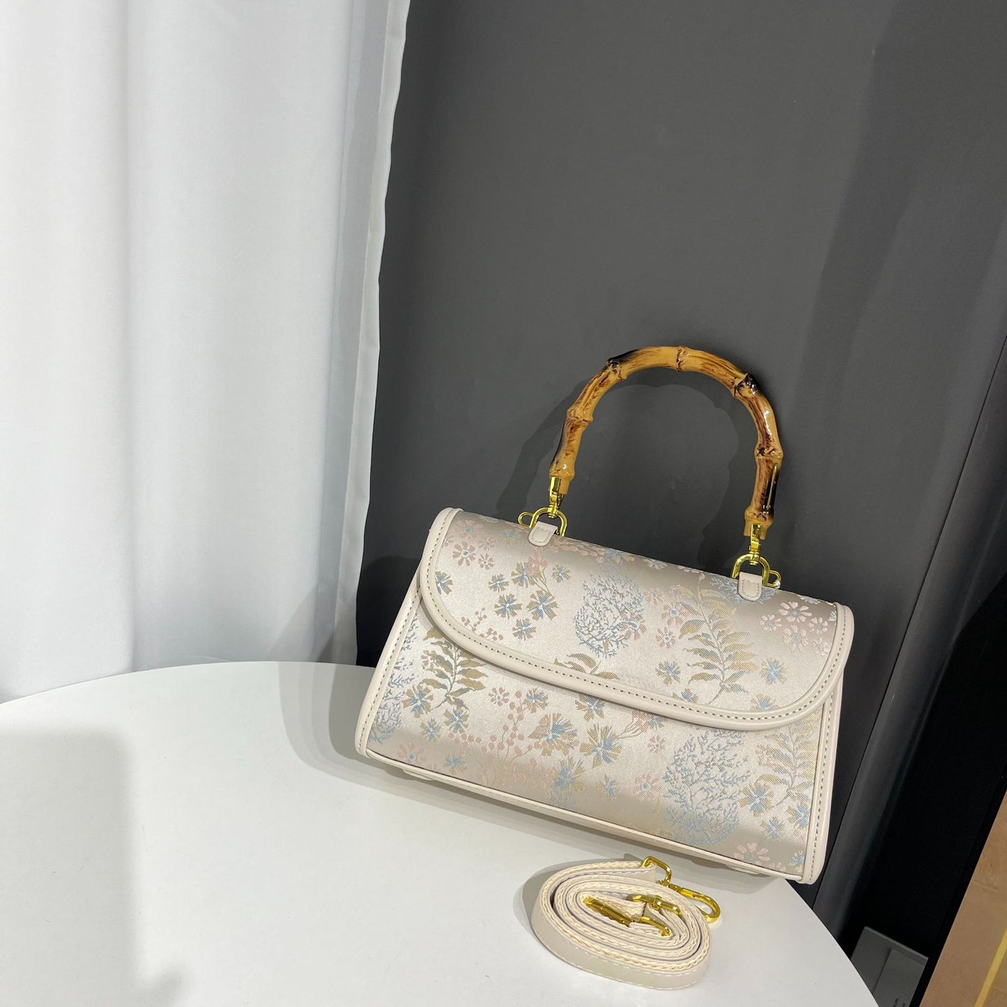 Floral embroidered handbag with bamboo handle on a white surface