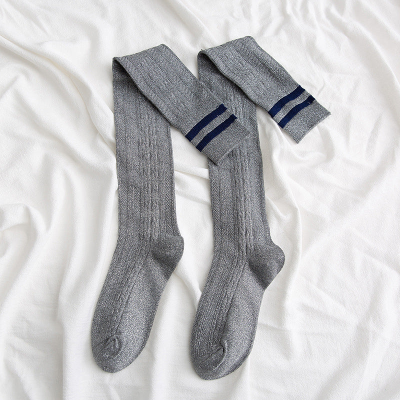 Gray knee-high socks with blue stripes on a white bedspread