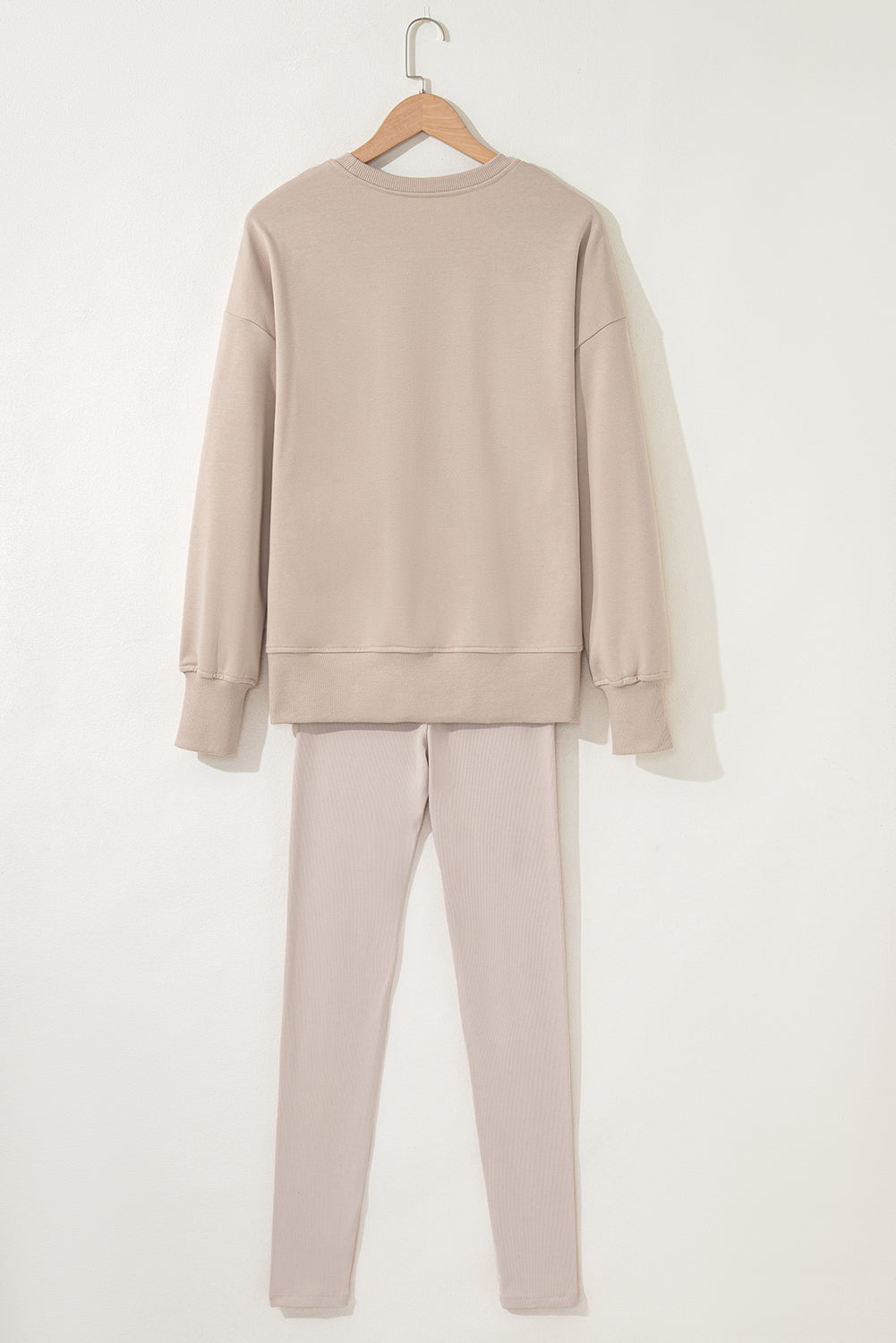 Beige sweatshirt and pants set on a hanger against a white background