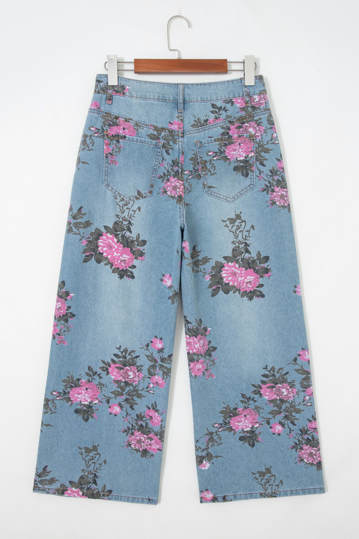 Floral-patterned jeans on a hanger against a white background back view