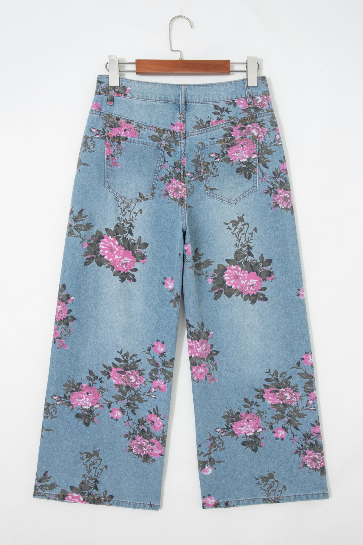 Floral-patterned jeans on a hanger against a white background back view