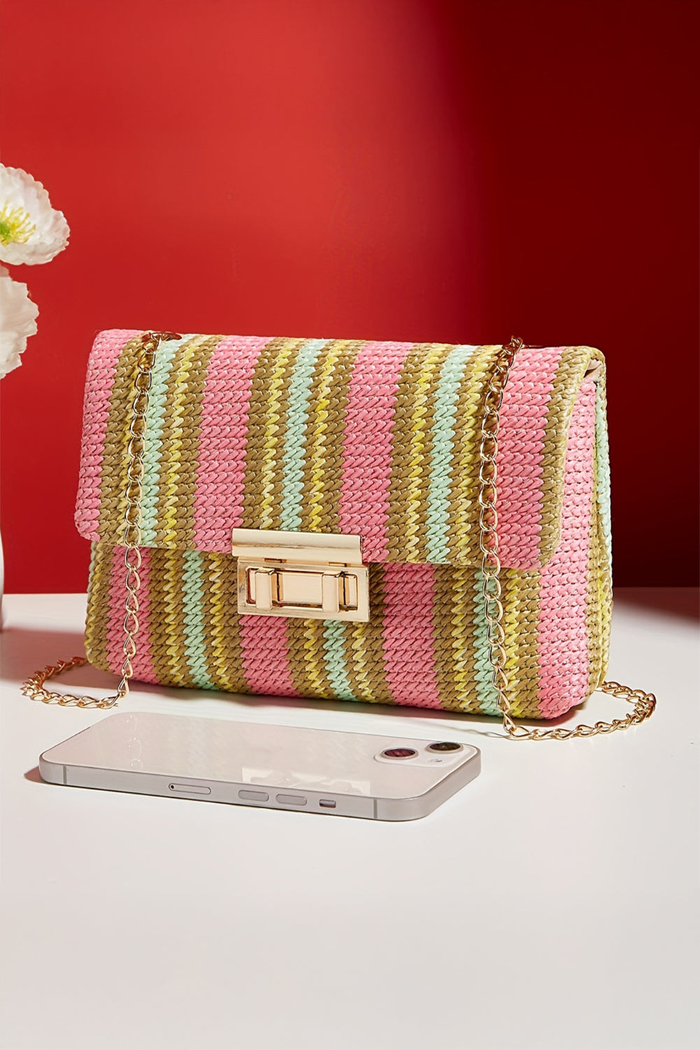 Striped colorful handbag with a phone on a red background