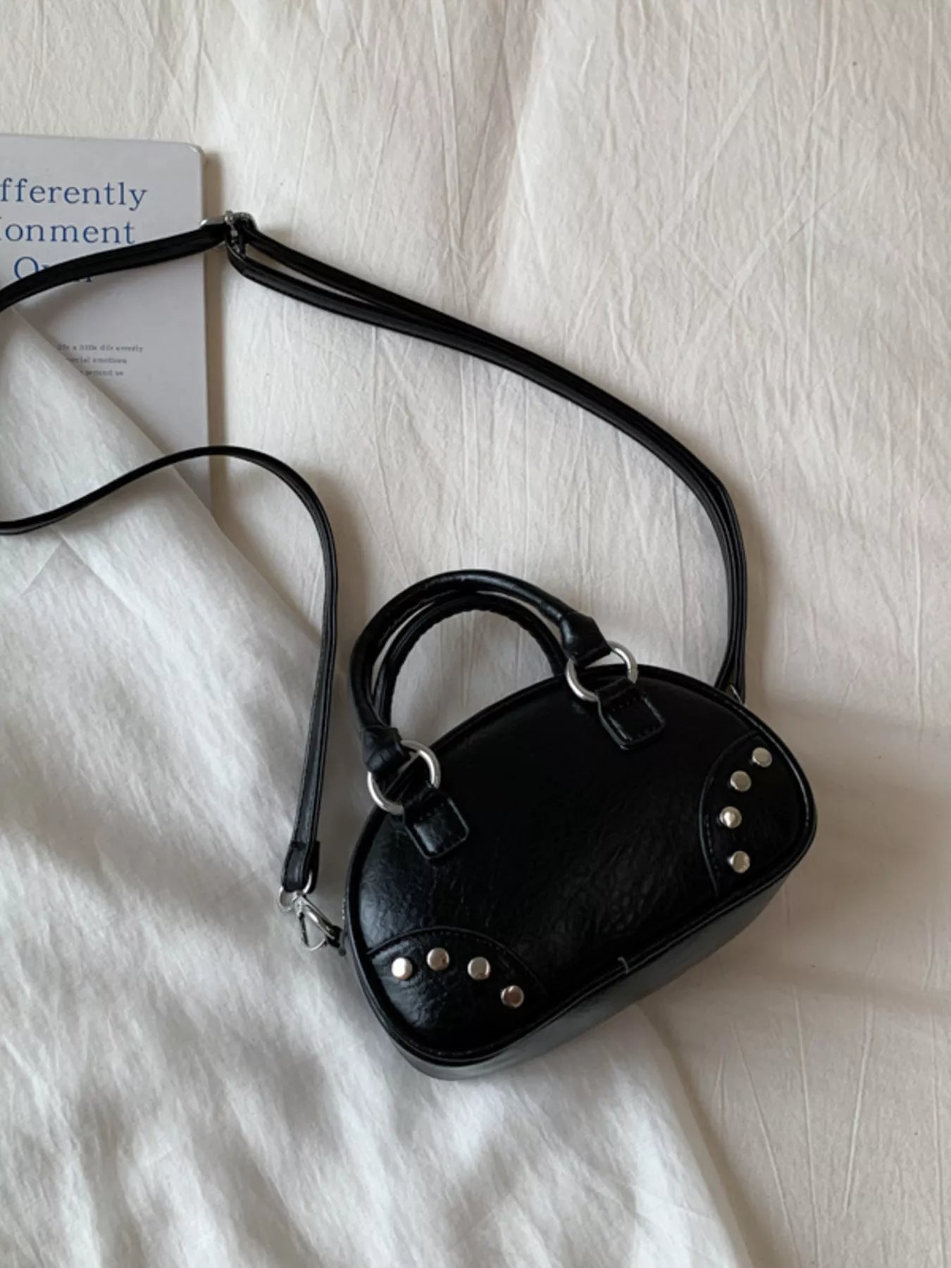 Black handbag with studs on a light fabric background