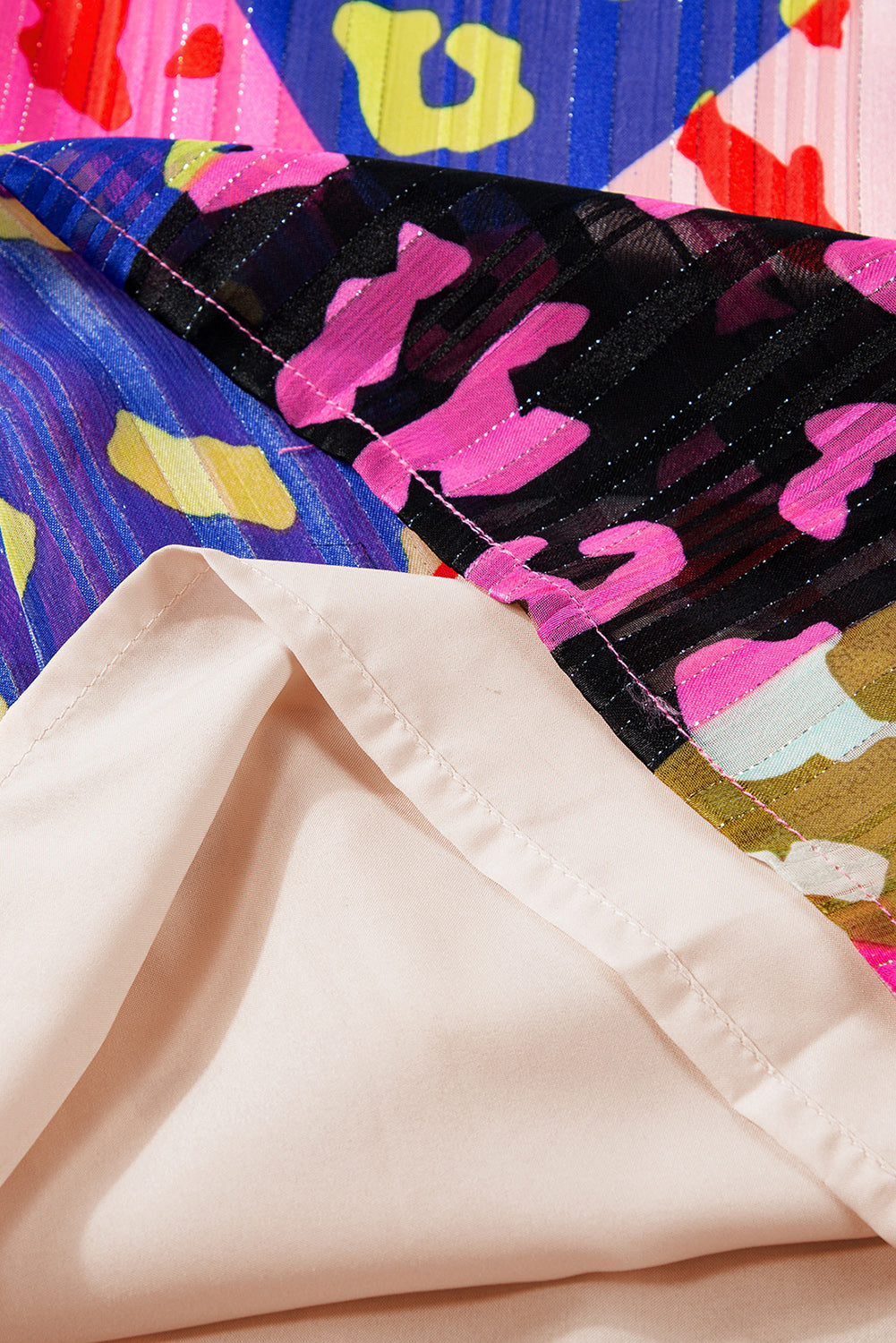 Close-up of colorful fabric with abstract patterns and a beige fabric texture.