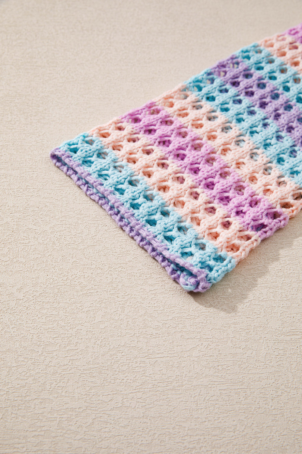Colorful crocheted blanket on a beige surface