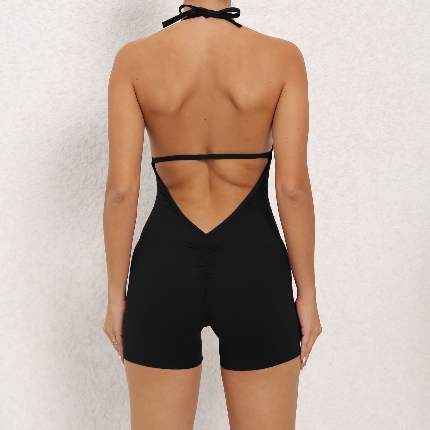 Black open-back romper worn by a person on a light gray background