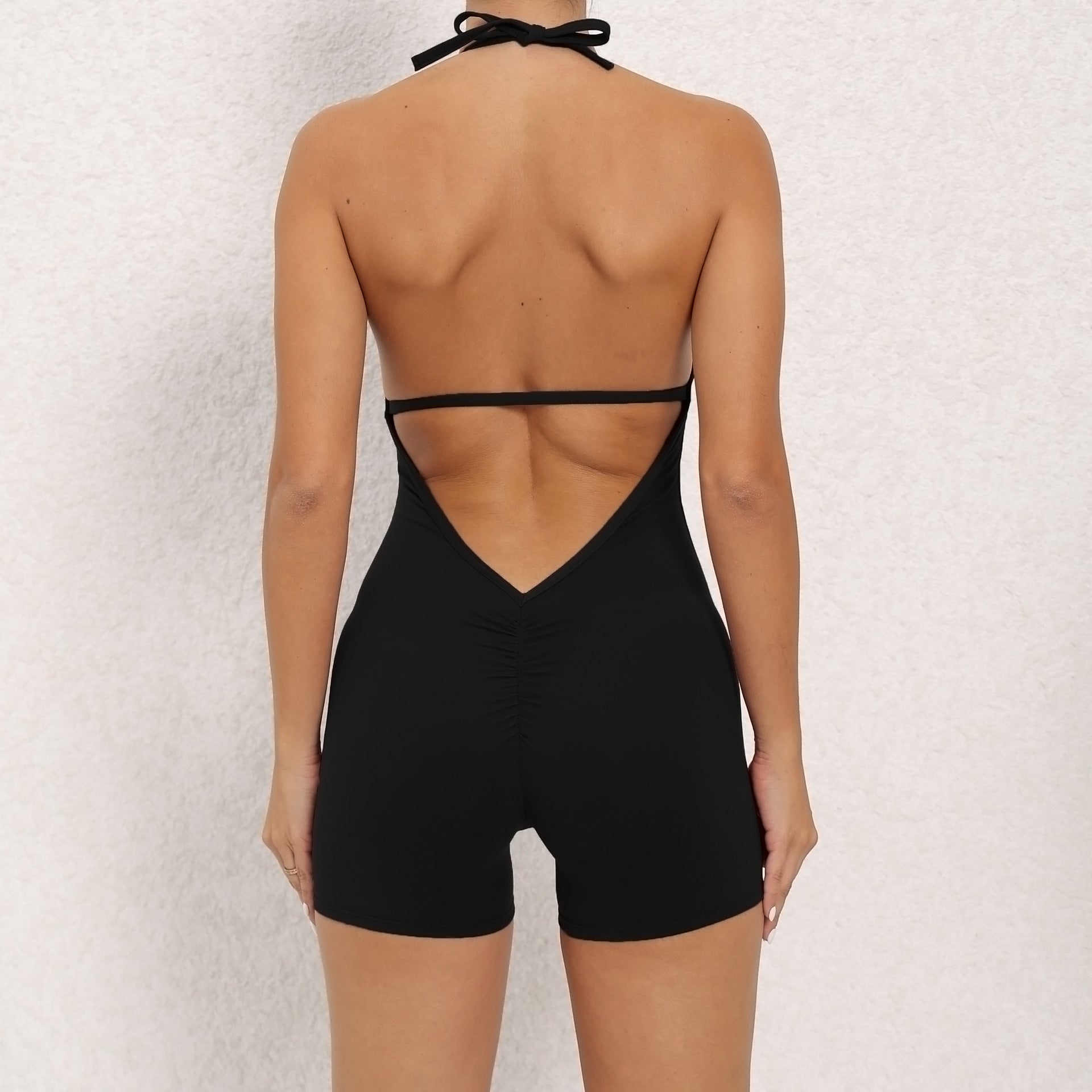 Black open-back romper worn by a person on a light gray background