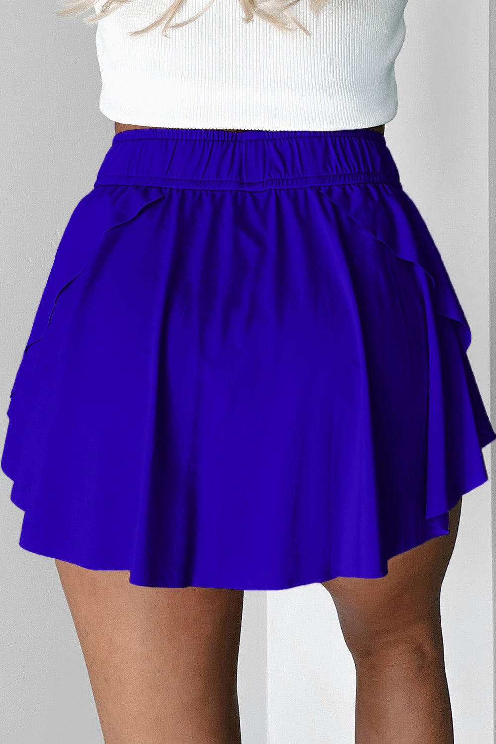 Purple tennis skirt worn by a person on a plain background back view 