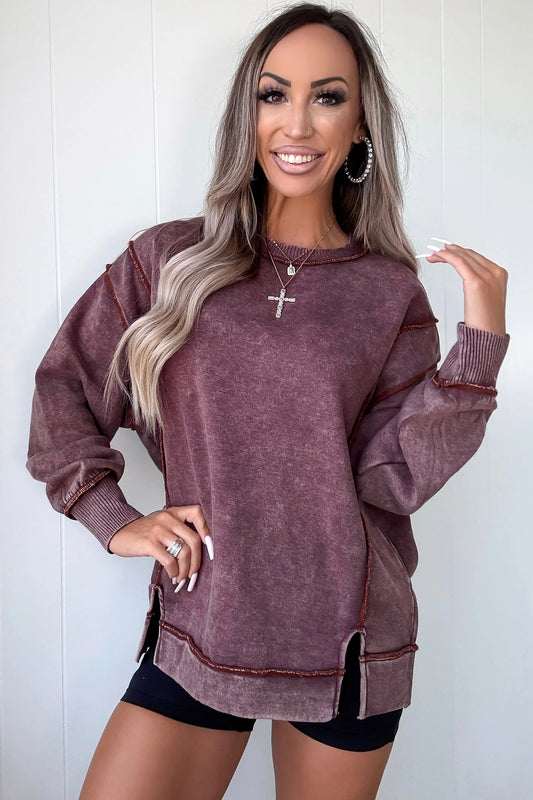 Woman wearing a maroon oversized sweater against a white background