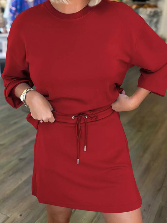 Red dress with a belt worn by a person, blurred background