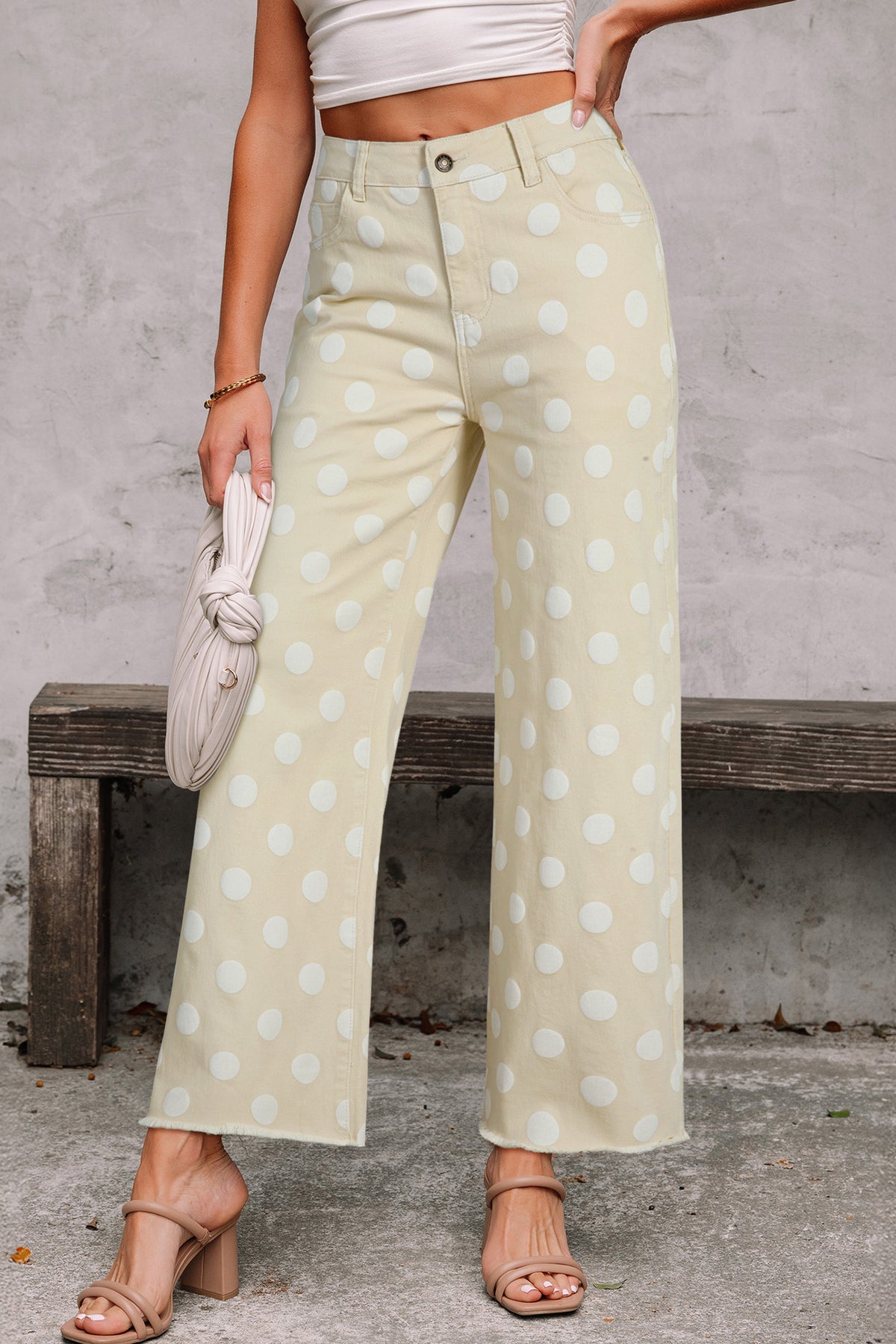 Person wearing light-colored polka dot pants against a gray wall. Front viw