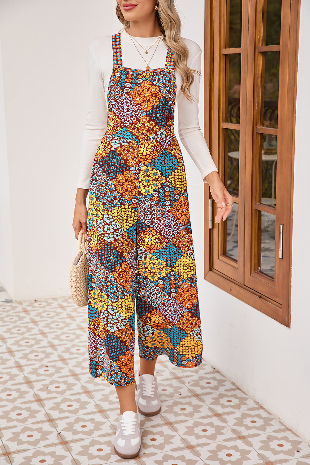 Woman wearing a colorful floral dress with a white top and sneakers, standing in a room with wooden doors.