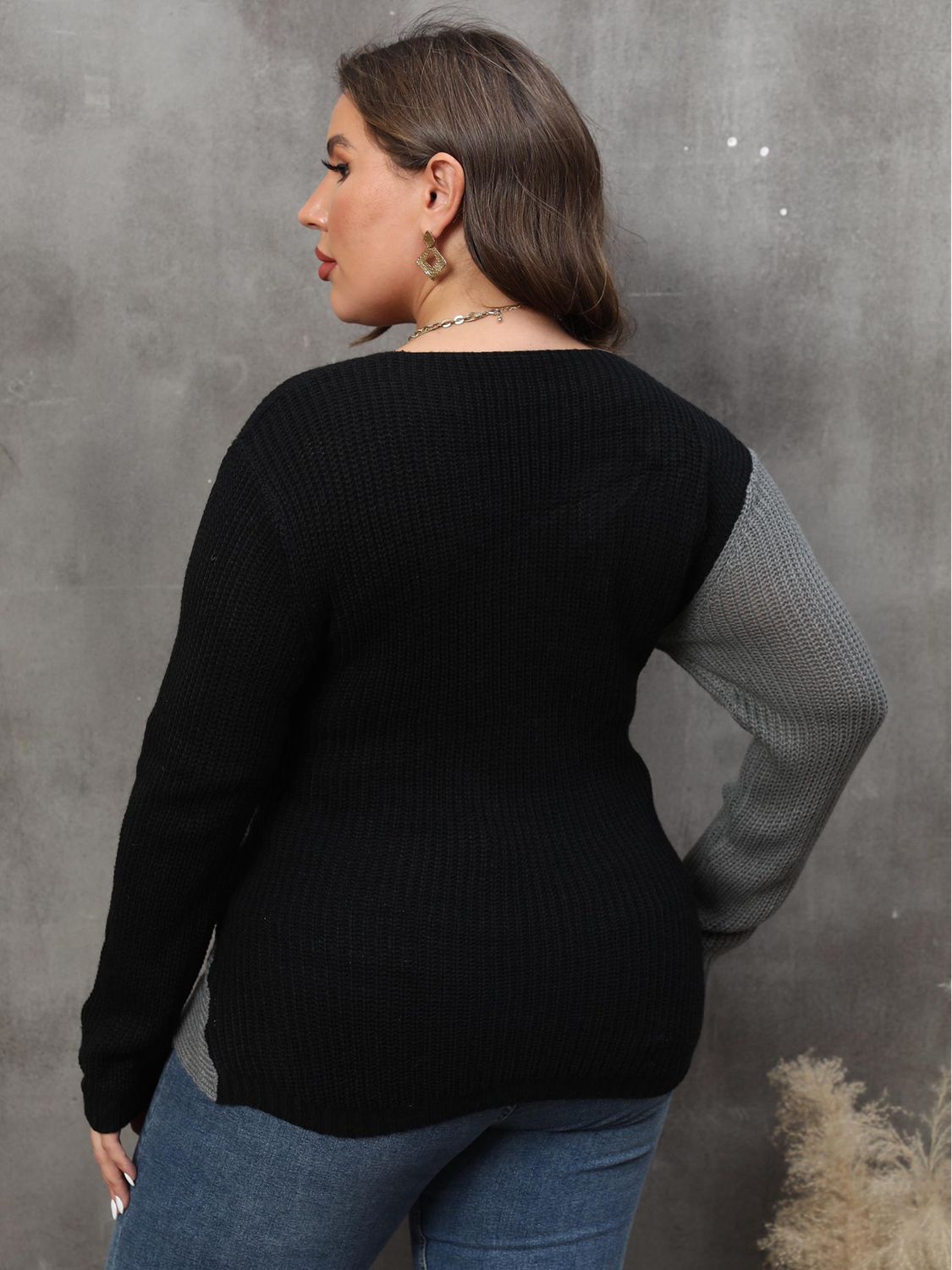 Back view of a model wearing a black and grey colorblock sweater.