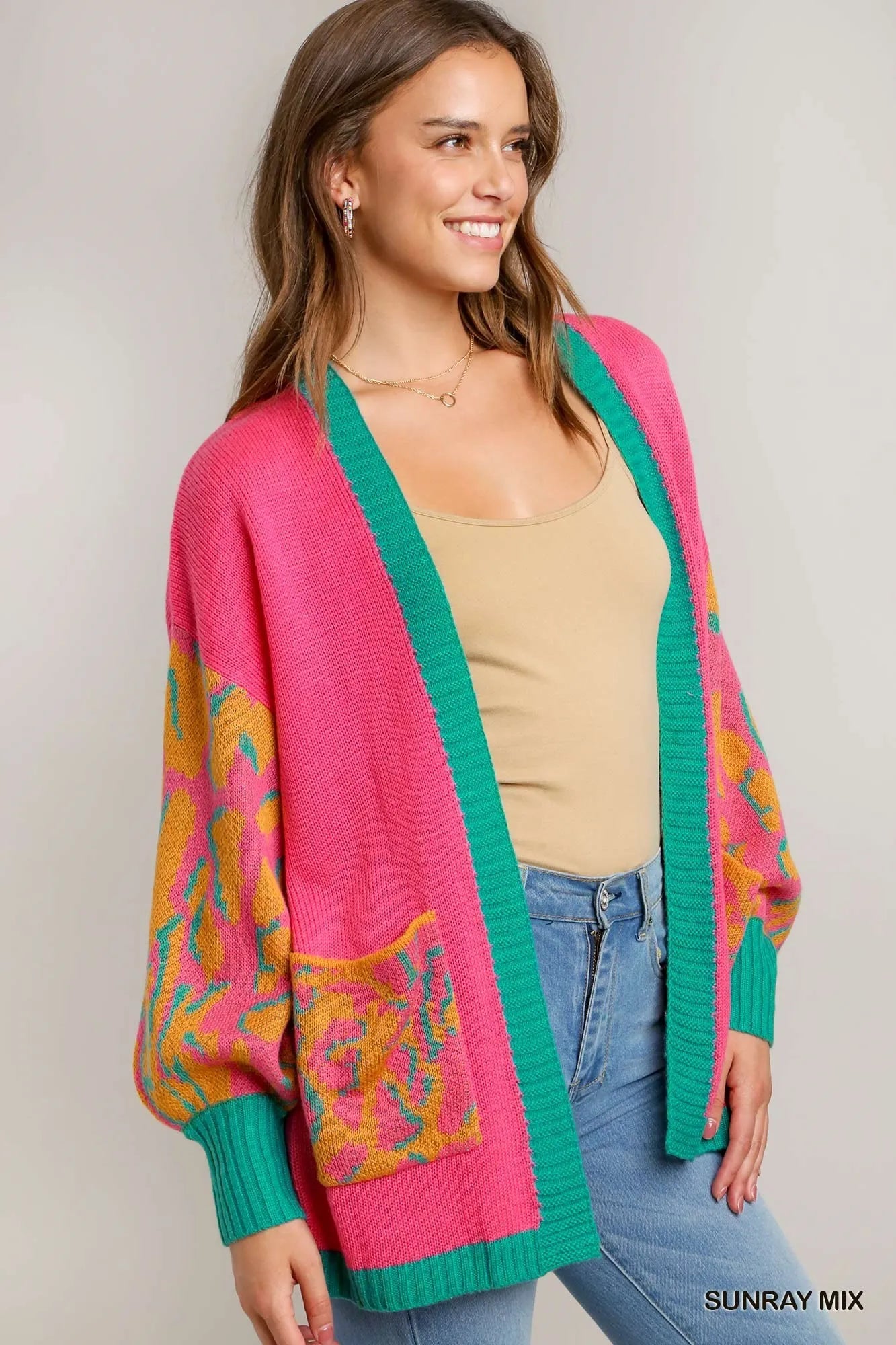 Model wearing a vibrant pink cardigan with turquoise accents.