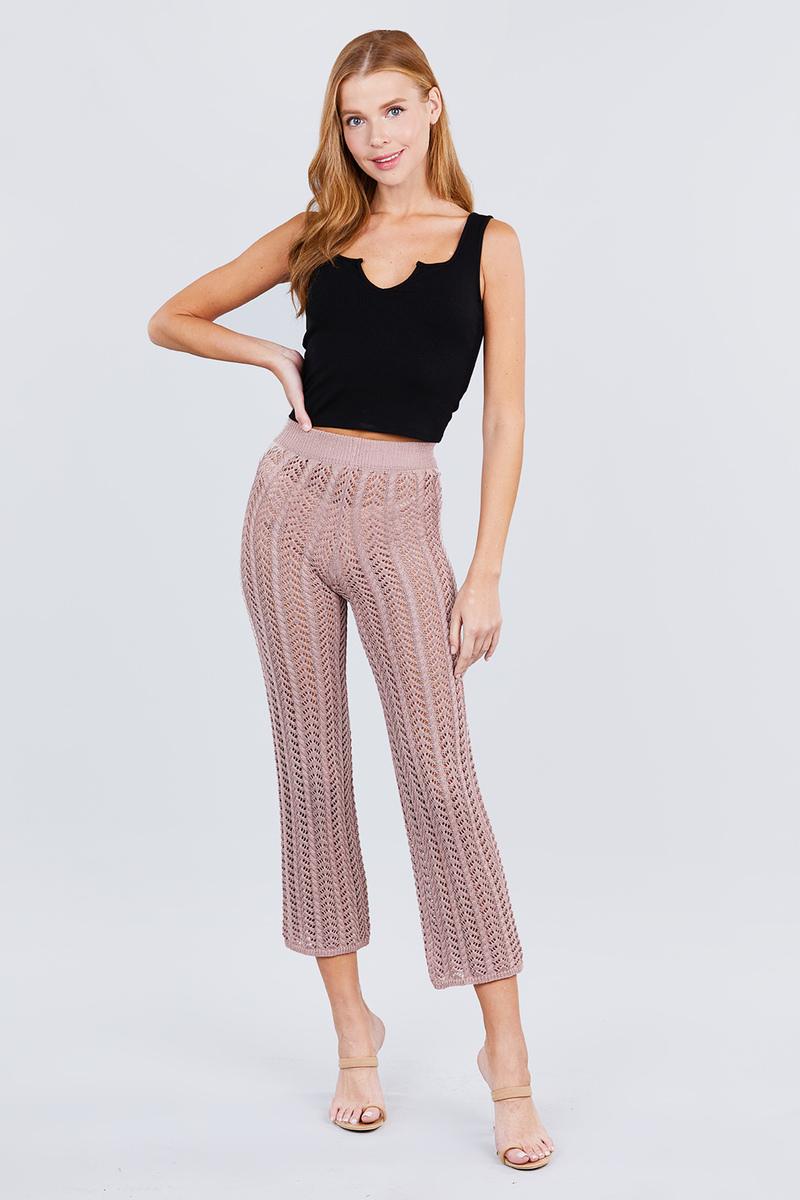 Woman wearing a black top and pink knitted pants on a white background