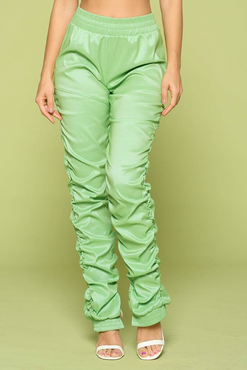 Light green faux leather pants worn by a person on a matching background