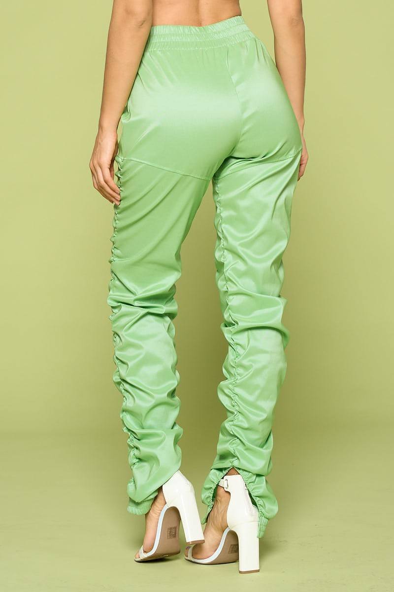 Light green faux leather pants worn by a person on a matching background side view