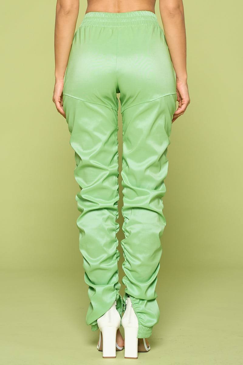 Green faux leather pants worn by a person on a green background back view