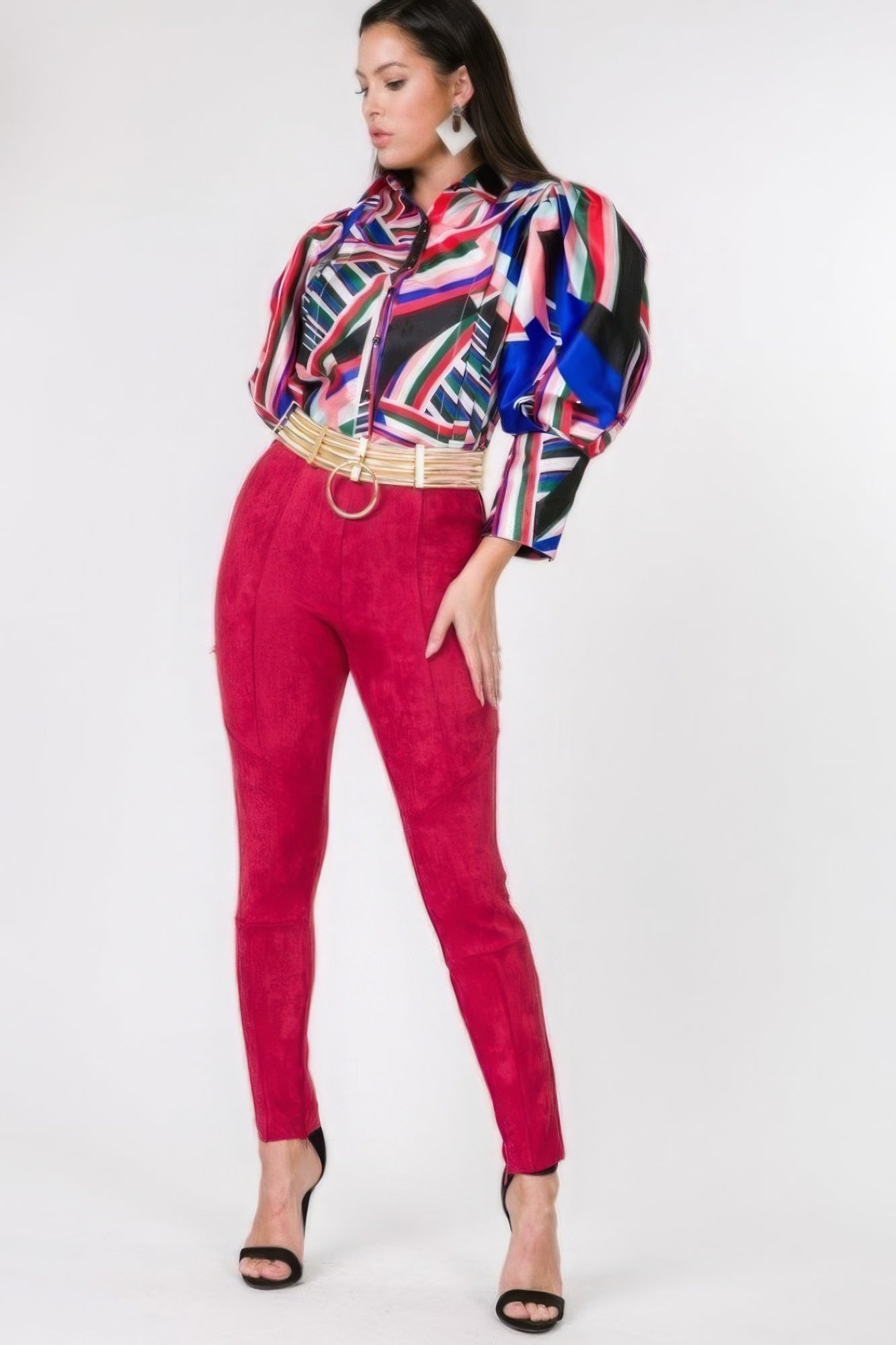 Woman wearing a colorful blouse and red faux suede pants on a white background
