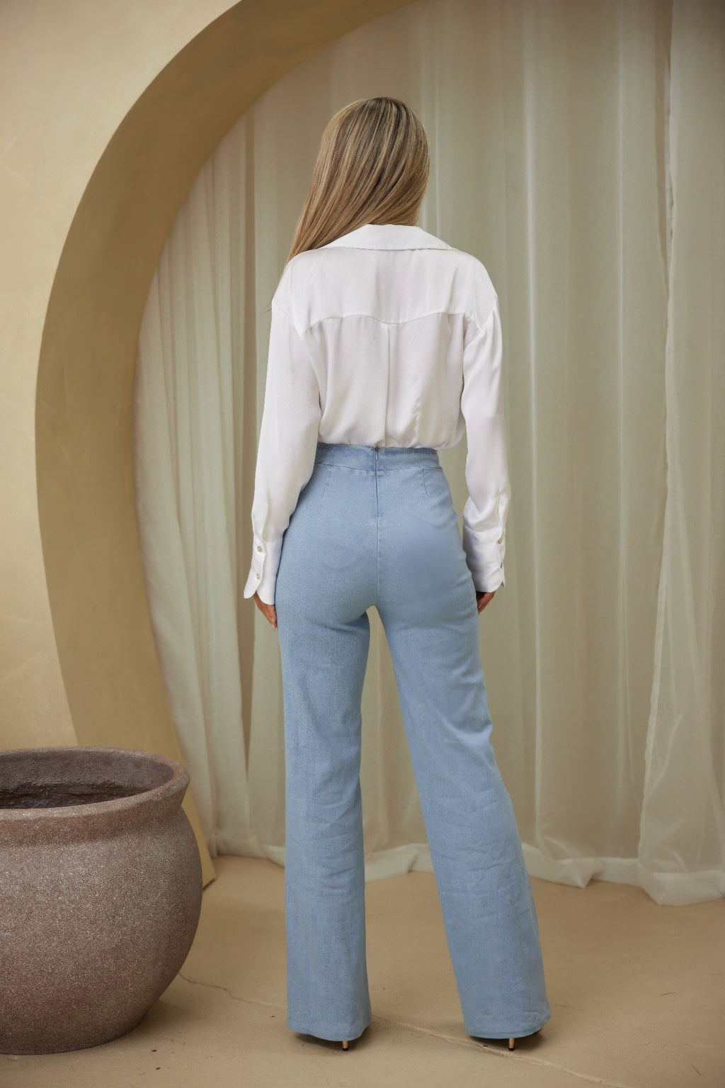 Person wearing a white blouse and light blue jeans rear view