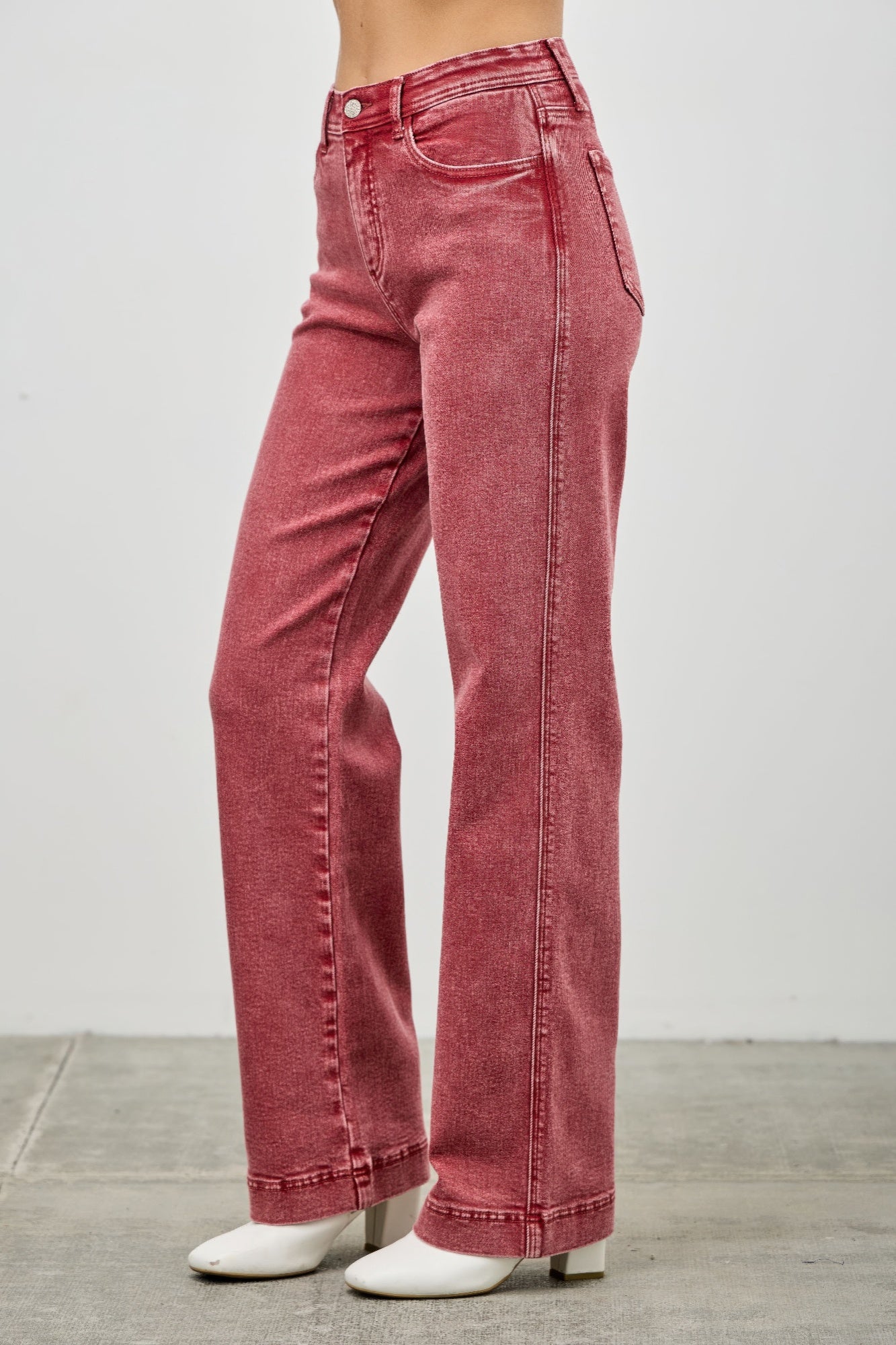 Red jeans worn by a person on a plain background side view