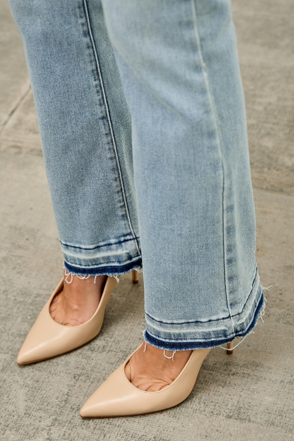 Close-up of light blue jeans hem and beige pointed-toe 