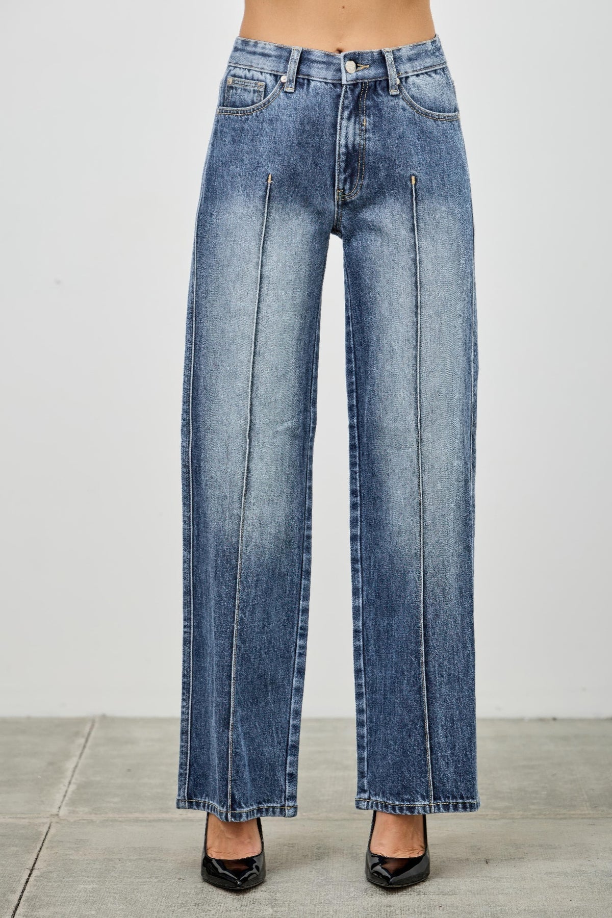 Blue pintuck jeans worn by a person on a light gray background