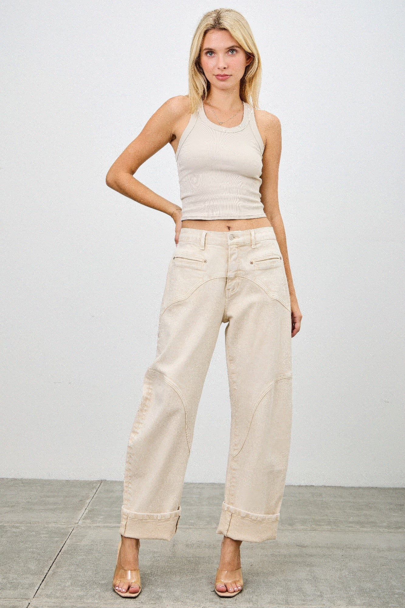 Woman wearing a beige tank top and western barrel jeans front view