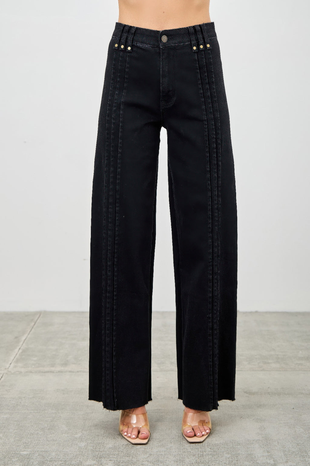 Black wide-leg jeans worn by a person on a gray background detail view