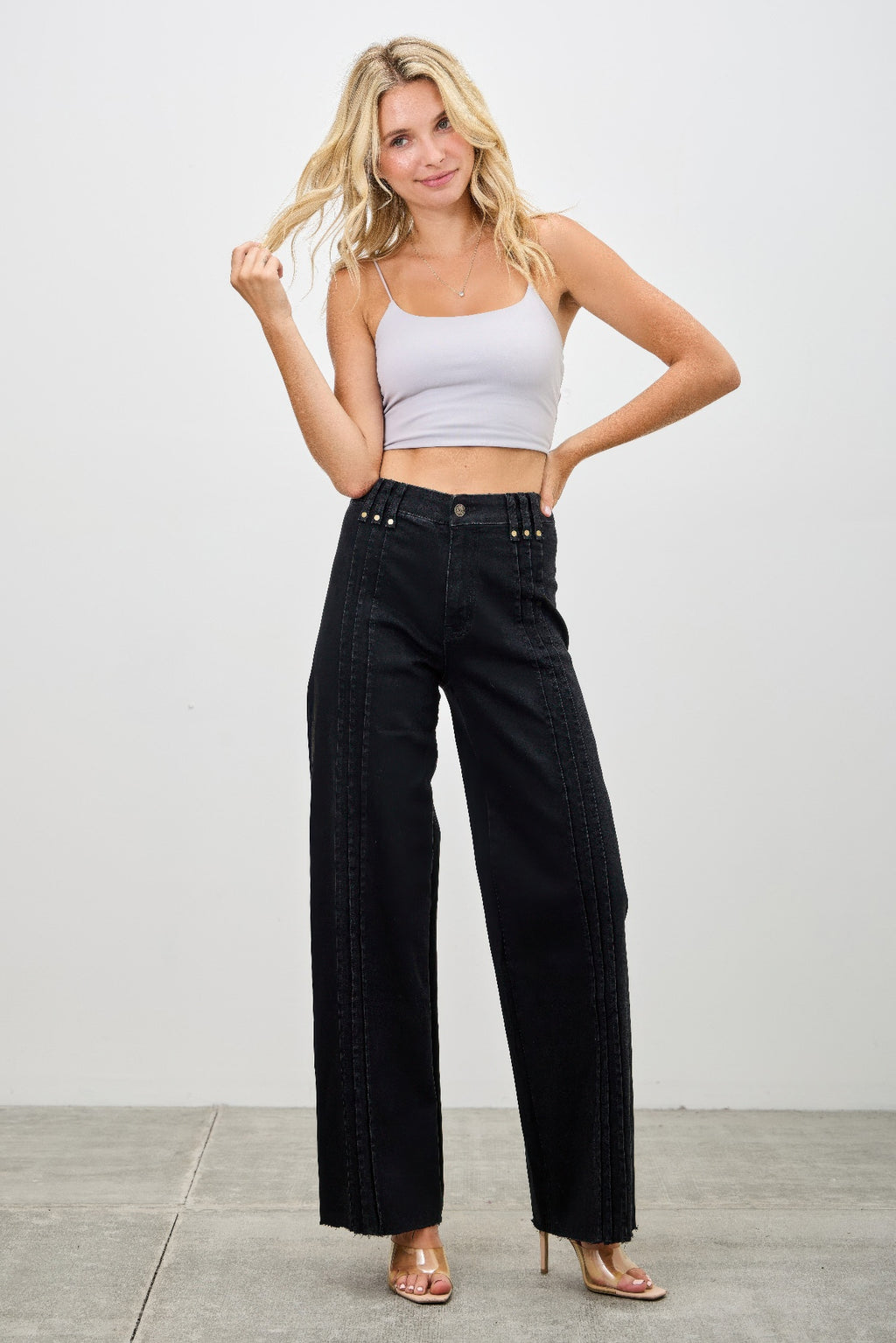 Woman wearing a white crop top and black high-waisted pants on a plain background front view